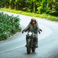 Beautiful female biker driving a cafe' racer motorbike - Pretty girl driving a motorbike and enjoying the roadtrip